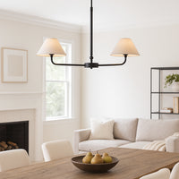 Matt Black Two Light Linear Pendant with tapered fabric shades hanging above a wooden dining table in a modern living space. Ideal classic linear ceiling light for dining rooms or kitchen islands.