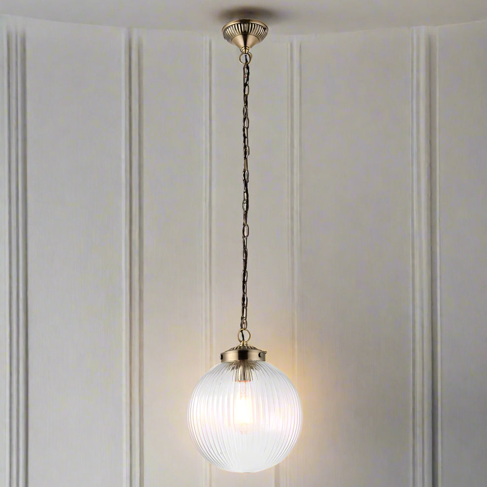 Ribbed glass globe pendant with antique brass fittings. Unusual ribbed circular globe light, disperses light softly in your space, ideal hall light or in a kitchen, over an island, a versatile light to suit any decor.