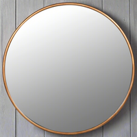 A supersized statement circular mirror finished in an antique brushed gold gilt solid metal frame on a neutral background


