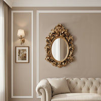 Decorative gold mirror on a wall with a sofa and framed picture in the background