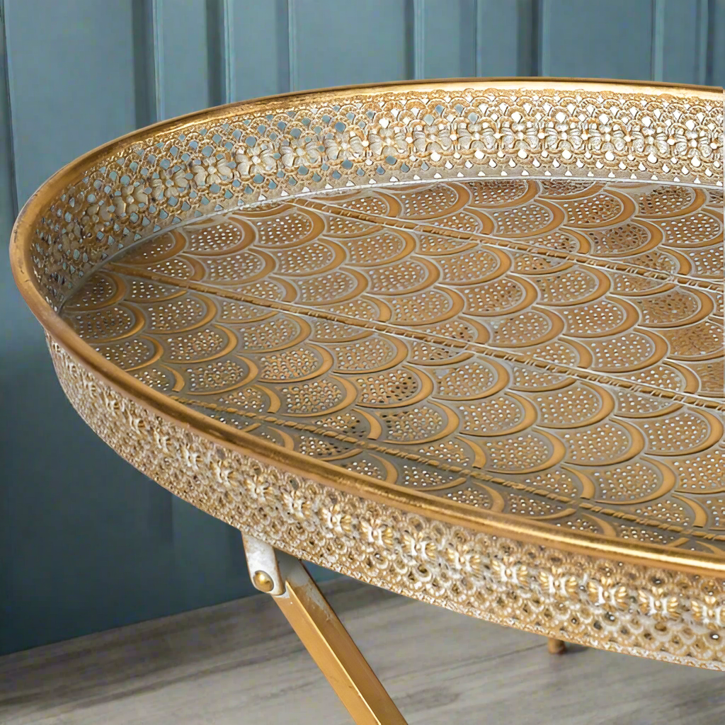 This is an elegantly ornate tray table that folds up neatly to save space when not in use.&nbsp; Finished in a gold gilt coloured pierced metal, this occasional table is perfect for evening drinks outside in your garden or terrace.

H: 68 cm W: 64 cm D: 33 cm&nbsp; 