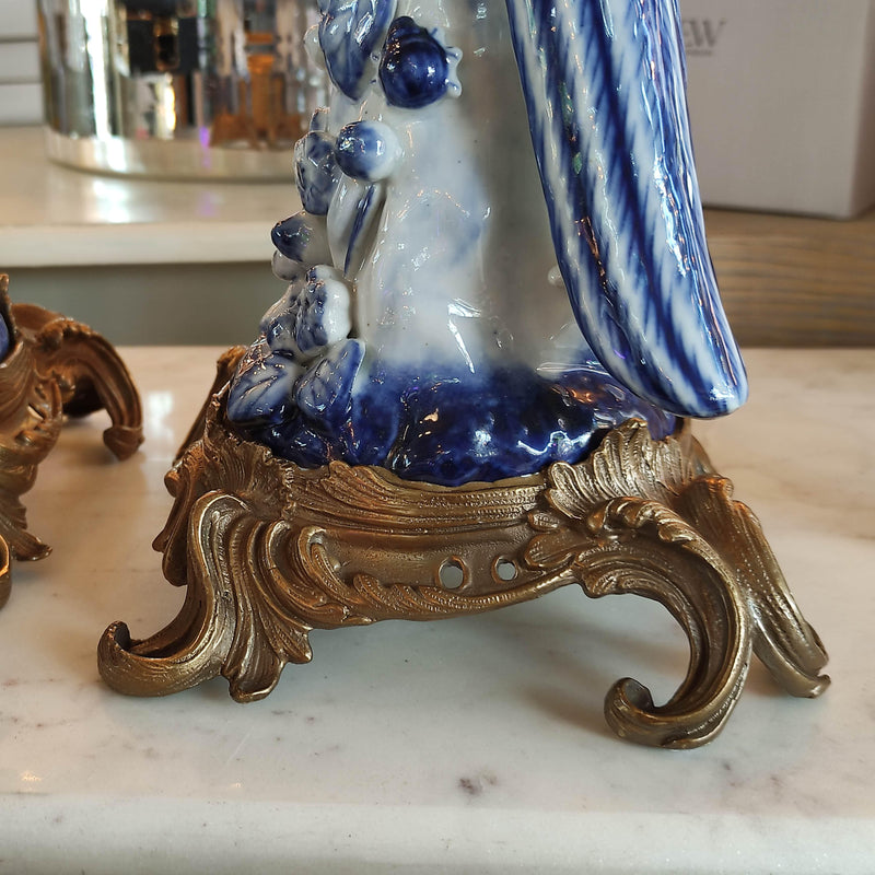 Decorative blue and white ceramic figure on a gold stand with a blurred background