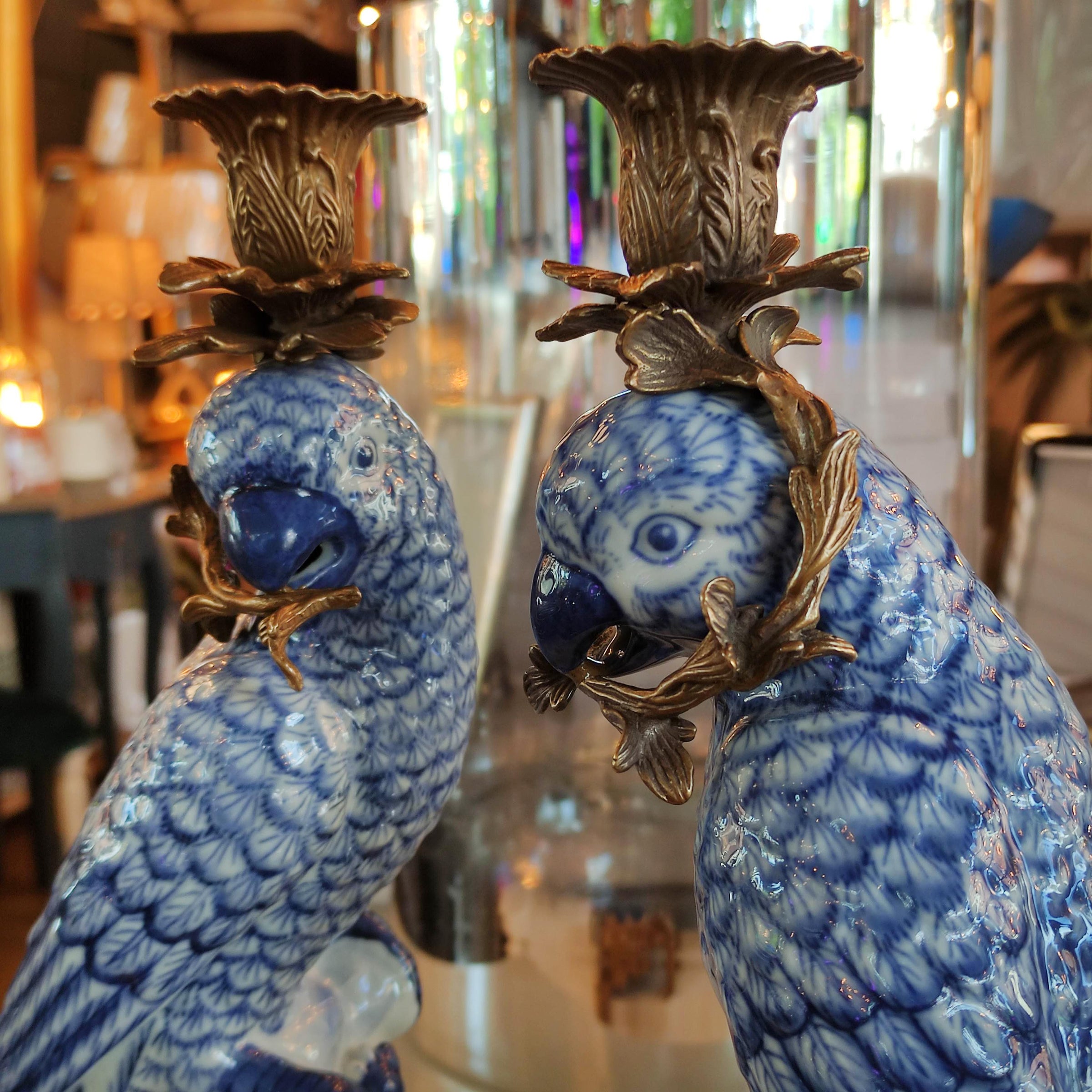 Two blue and white ceramic parrot figurines with gold accents in a store setting.
