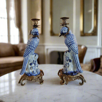 Pair of blue and white parrot candle holders on a marble surface with a blurred indoor background.