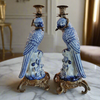Pair of blue and white ceramic parrot candle holders on a marble surface.