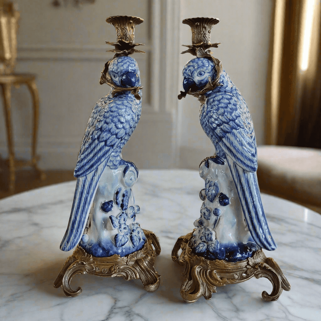 Pair of blue and white ceramic parrot candle holders on a marble surface.