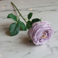 This ultra-realistic artificial lilac rose features rich, velvet-like petals and a vibrant green stem with textured leaves