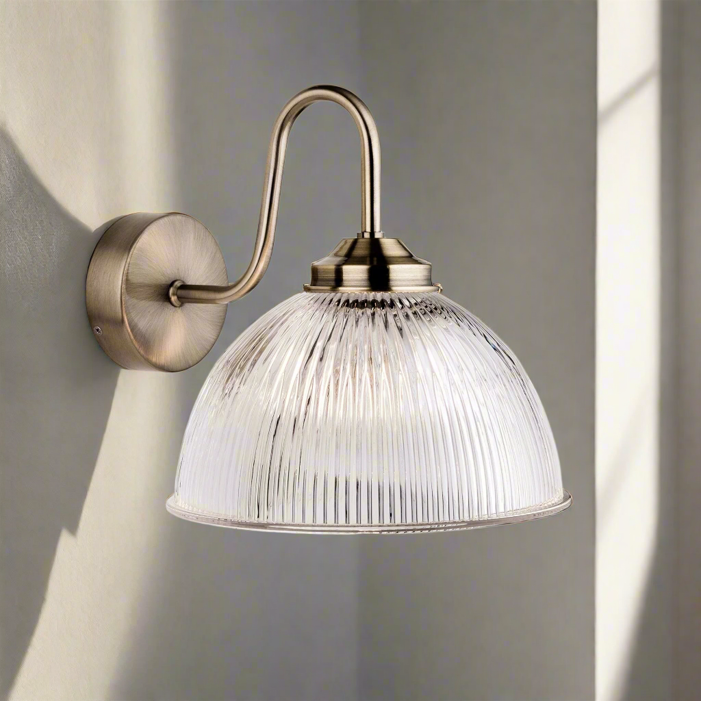 This stylish antique brass and ribbed clear glass wall light creates an instant classy and elegant feel&nbsp; Unusual to have a wide, ribbed glass fitting with an antique brass metal fitting. Perfect vintage look for a kitchen or dining room.&nbsp; The ribbed glass diffuses the light and offers a elegant ambient glow, great for wall lighting in a living room.