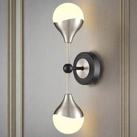 Satin nickel dual wall light with black matt metal accents and two opal glass globes, mounted on a sleek circular base. Ideal for modern home decor.