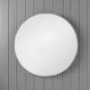 A decorative silver metal circular mirror with a bamboo frame, placed against a wooden background.
