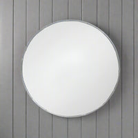 A decorative silver metal circular mirror with a bamboo frame, placed against a wooden background.