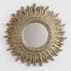 Decorative sun-shaped mirror with a gold finish on a white background