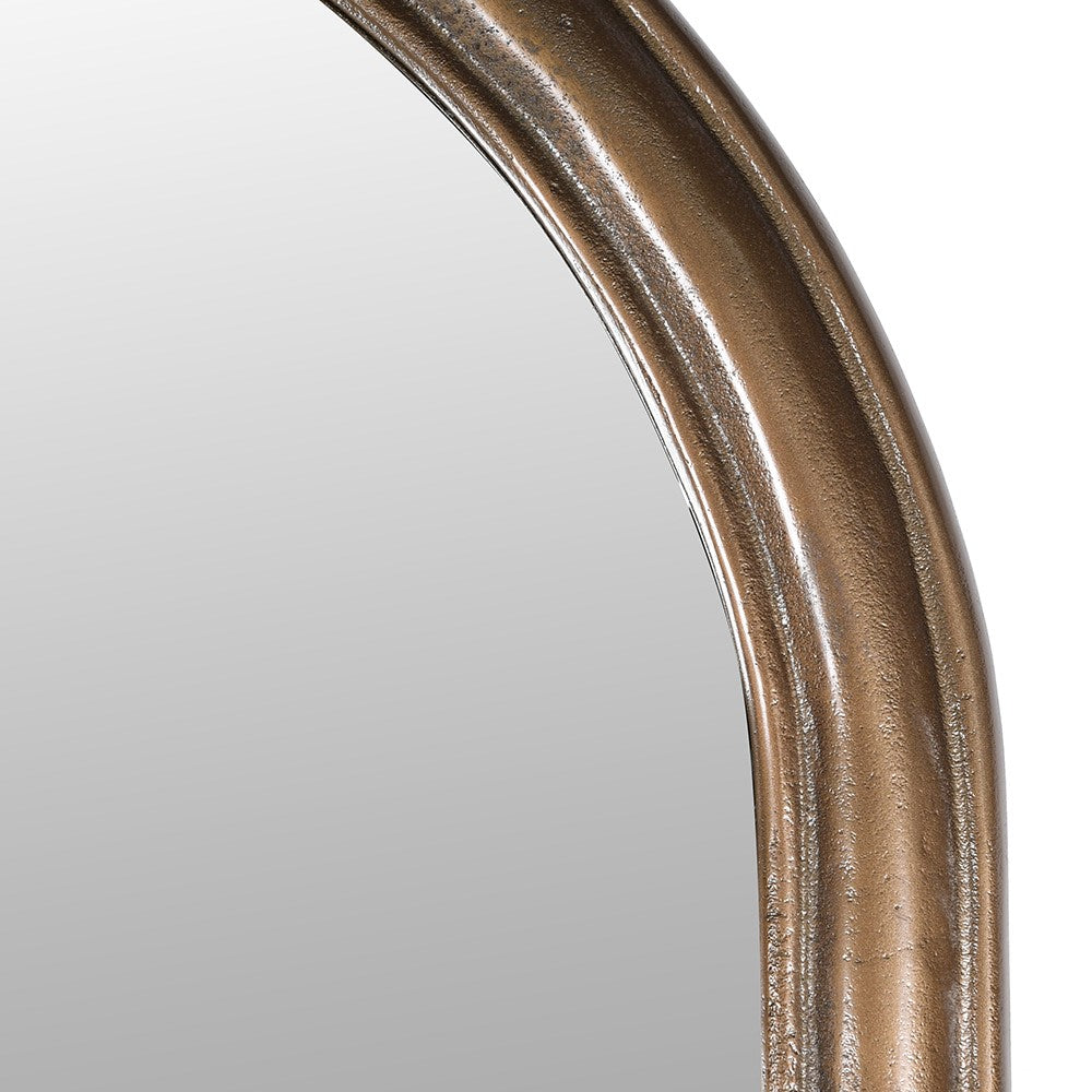 Detail of the frame of the tall brass arched mirror.
