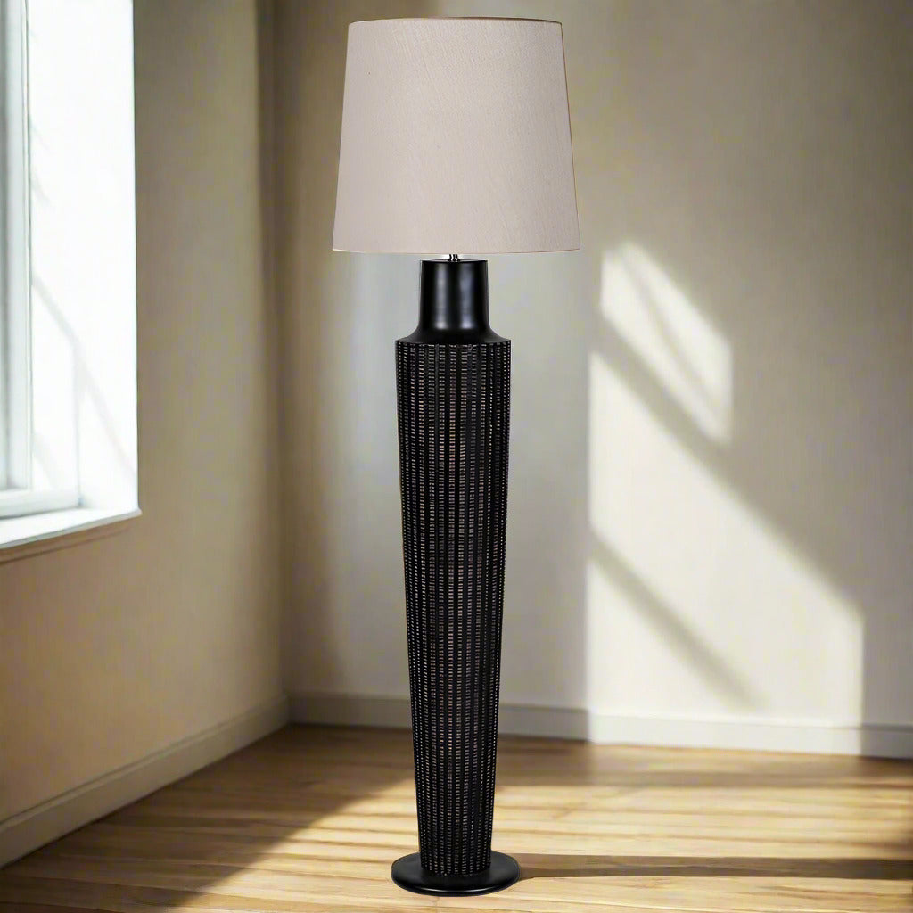 Tall black rattan floor lamp and linen shade, the base of the lamp is an oversize black column, a great contemporary look.&nbsp; The addition of the natural pale linen shade contrasts well with the black base to add to the overall dramatic look of the lamp.&nbsp; Floor lamps, whether in a sitting room, dining room or bedroom are the perfect way of adding extra light to your interior.