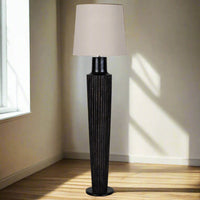 Tall black rattan floor lamp and linen shade, the base of the lamp is an oversize black column, a great contemporary look.&nbsp; The addition of the natural pale linen shade contrasts well with the black base to add to the overall dramatic look of the lamp.&nbsp; Floor lamps, whether in a sitting room, dining room or bedroom are the perfect way of adding extra light to your interior.