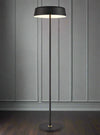 Black metal floor lamp with stylish, minimalist shade.&nbsp; The black stand having aged brass accents.&nbsp; The shade benefits from a white interior to brighten the light and there is an in-line dimmer switch on the cable. An understated contemporary lamp that would work beautifully in contemporary or industrial style setting.&nbsp; 