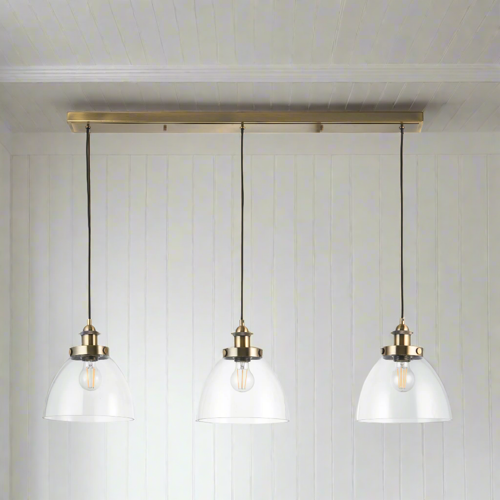 3 light, linear pendant in clear glass with antique brass metal accents and ceiling plate. To add light over your kitchen island or dining area. A real design led addition to your dining room or kitchen.