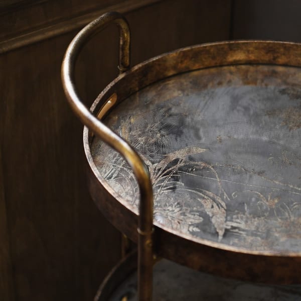A gilt drinks trolley withe three mirrored trays, that can be used independently to the trolley.&nbsp; The trays are mirrored glass with a tranquil waterside scene in gilt,&nbsp; the frame of the trolley is brushed gilt metal and the whole thing is set on four castors.&nbsp; Trolley such as these are called 'drinks' trolleys, but can also be used to display all your toiletries in a bathroom, to display plants in a conservatory, they have diverse uses.&nbsp; Not forgetting three useful trays.