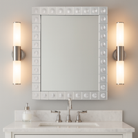 This is a Venetian-style wall mirror featuring a striking raised decorative frame. The rectangular mirror is bordered by a geometric design of square mirrored tiles, each accented with a raised circular dome detail that adds dimension, texture, and light-catching elegance. The reflective frame enhances the mirror’s brilliance, making it not only functional but also a bold decorative statement.

Its clean lines and sculptural frame give it a contemporary twist on classic Venetian design, making it versatile 