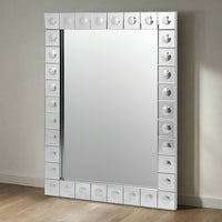 This is a Venetian-style wall mirror featuring a striking raised decorative frame. The rectangular mirror is bordered by a geometric design of square mirrored tiles, each accented with a raised circular dome detail that adds dimension, texture, and light-catching elegance. The reflective frame enhances the mirror’s brilliance, making it not only functional but also a bold decorative statement.

Its clean lines and sculptural frame give it a contemporary twist on classic Venetian design, making it versatile 