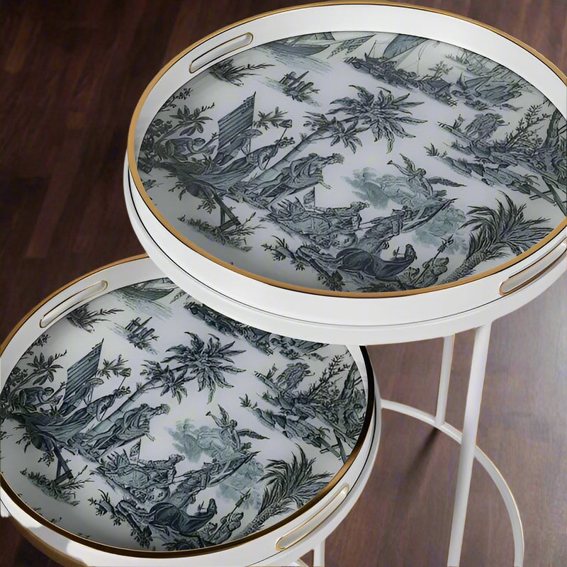 A very unusual set of two side tables, one nested below the other, circular tables on a white metal frame.&nbsp; The trays, which are detachable and can be used independently, have a traditional blue and white willow pattern style print on them. They are set off with a gold rim to the edge of the trays which lifts them and gives them a luxurious look. They combine modern minimalism with a classic scenic decorative top. Perfect in a contemporary setting, a cottage or period home.&nbsp;
