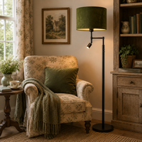 Directional black floor lamp with green shade in a country cottage cosy corner next to a classic armchair.