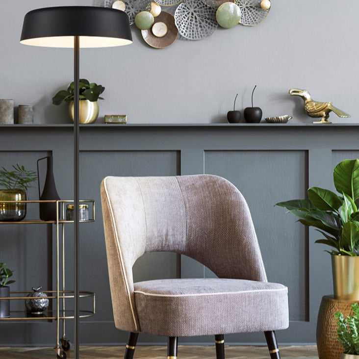 Black floor lamp with minimalist disc-shaped shade in a reading corner