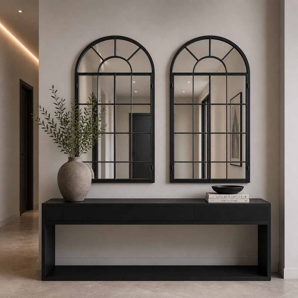 A pair of arched black window mirrors over  a console table in a contemporary hall.