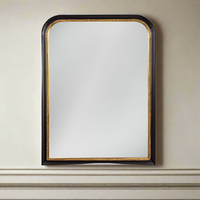 Arched wall mirror with a black frame and fine gold beaded inner trim, styled above a paneled wall.