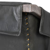Close-up of a black leather jacket with wooden collar and brass buttons.