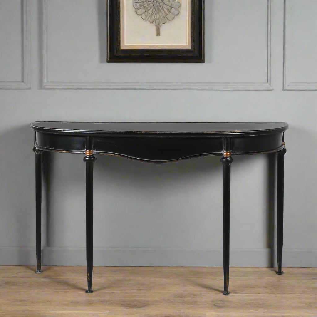Refined, versatile, and effortlessly elegant, this medium metal console table is the perfect accent piece for modern and traditional interiors alike. Designed with a slim black metal frame and a gracefully curved silhouette, it offers a sophisticated focal point while keeping your hallway or entryway light and uncluttered.
The gently distressed black finish with delicate gold accents adds a touch of vintage character, making each piece feel unique.