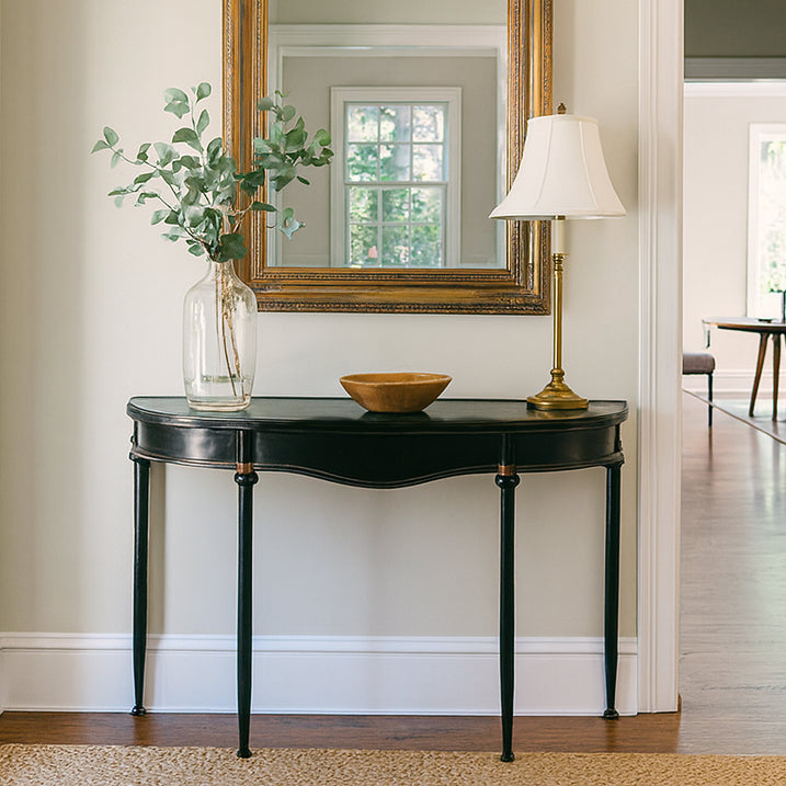 Refined, versatile, and effortlessly elegant, this medium metal console table is the perfect accent piece for modern and traditional interiors alike. Designed with a slim black metal frame and a gracefully curved silhouette, it offers a sophisticated focal point while keeping your hallway or entryway light and uncluttered.
The gently distressed black finish with delicate gold accents adds a touch of vintage character, making each piece feel unique.