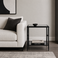 An empire style black metal and glass side table in a contemporary sitting room next to a white sofa.