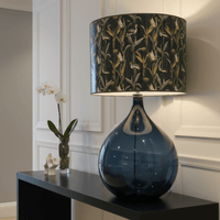 Decorative lamp, with velvet shade on a black console table in a hall setting. 