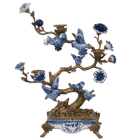 Blue and white bronze and porcelain bird tree candleholder against a white background.