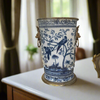 Decorative blue and white vase with bird and tree design on a table.