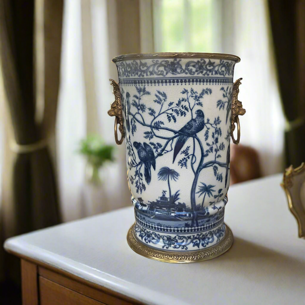 Decorative blue and white vase with bird and tree design on a table.