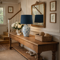 Blue and white ceramic table lamp on a wooden console in a country style, traditional hall.
