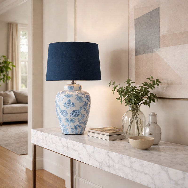 Blue and white ceramic table lamp on white console in contemporary hallway setting.