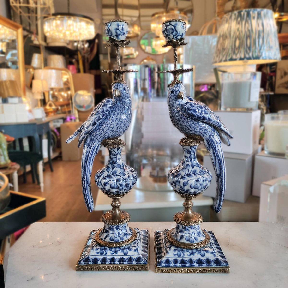 Decorative blue and white bird sculptures on a table with a blurred store background