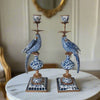 Pair of decorative candle holders with blue and white parrot design on a marble surface.
