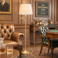 Brass floor lamp, with extending brass arm in a gentlemen's club setting, leather arm chairs and classic wooden furniture.
