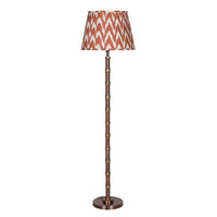 Tall faux bamboo-style metal floor lamp with an antique bronze and brass-toned stem, circular base and rust-and-cream patterned ikat fabric shade.