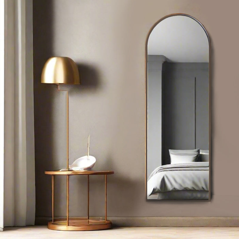 Tall arched bronze mirror in a bedroom
