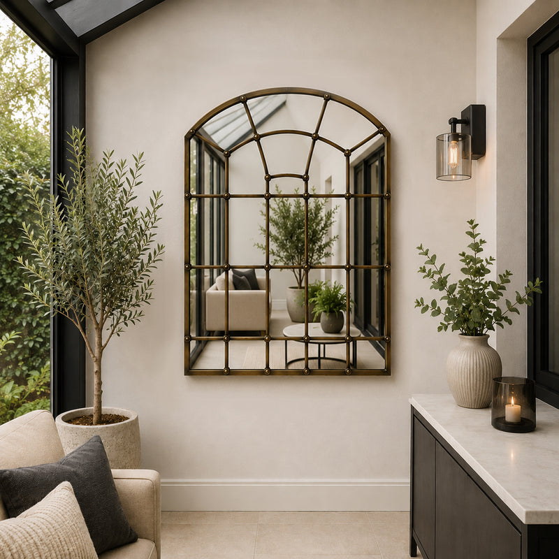 A great arched metal window mirror in an antique brass finish with studding to the frame. 