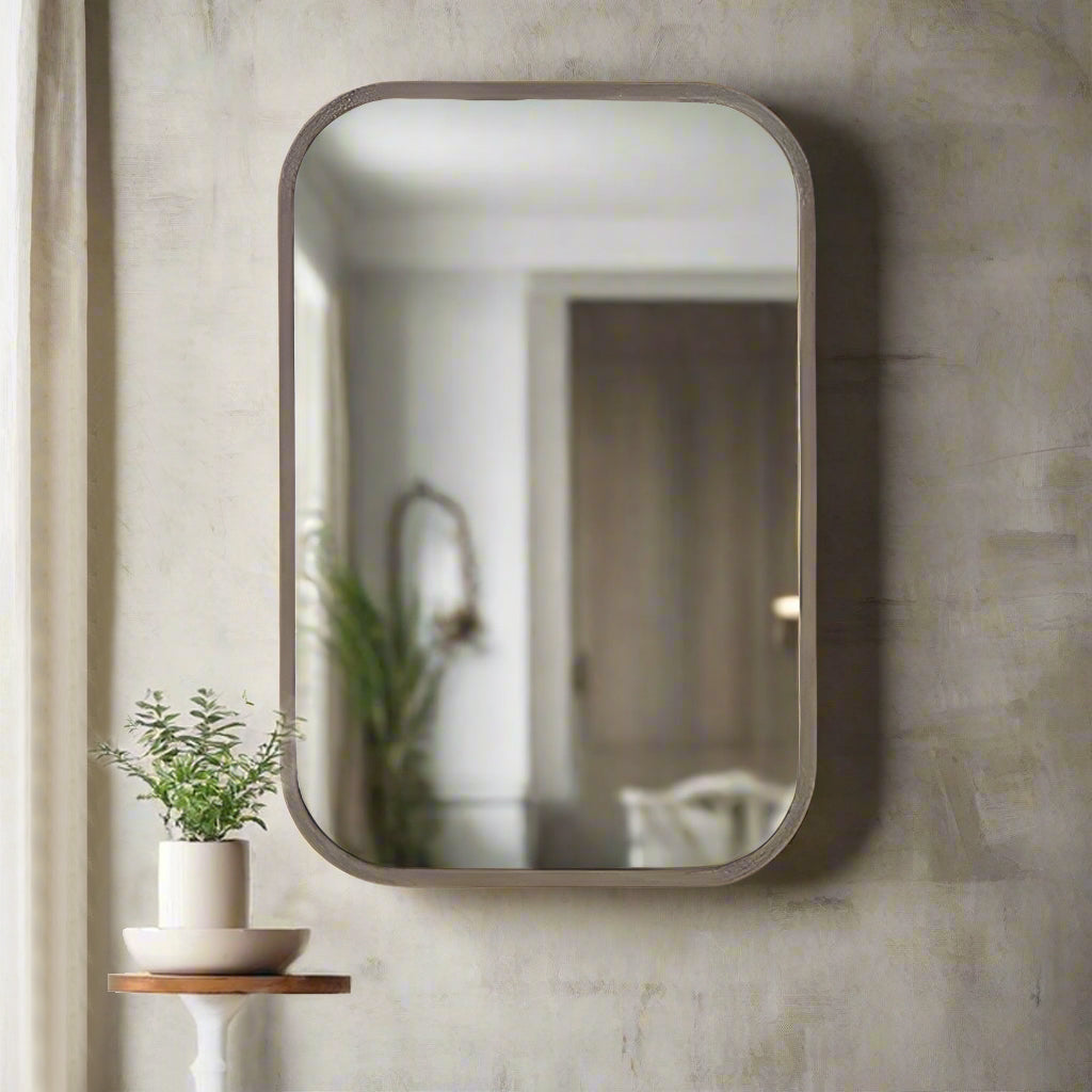Bronze metal wall mirror with curved corners in a hallway