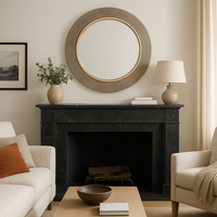 Brushed bronze mirror sitting over a black marble fireplace, in a cosy living room.