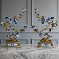 Pair of ornate candle holders with blue and white floral designs on a marble surface.