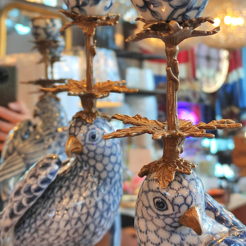 Stunning blue and white porcelain parrot candleholders with gilt bronze finials. Exceptional quality — a true statement piece for any room. Close up of tops of the birds.

