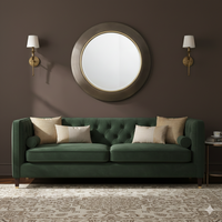 Brushed bronze mirror hanging between two wall lights on a cocoa coloured wall over a luxurious velvet sofa.
